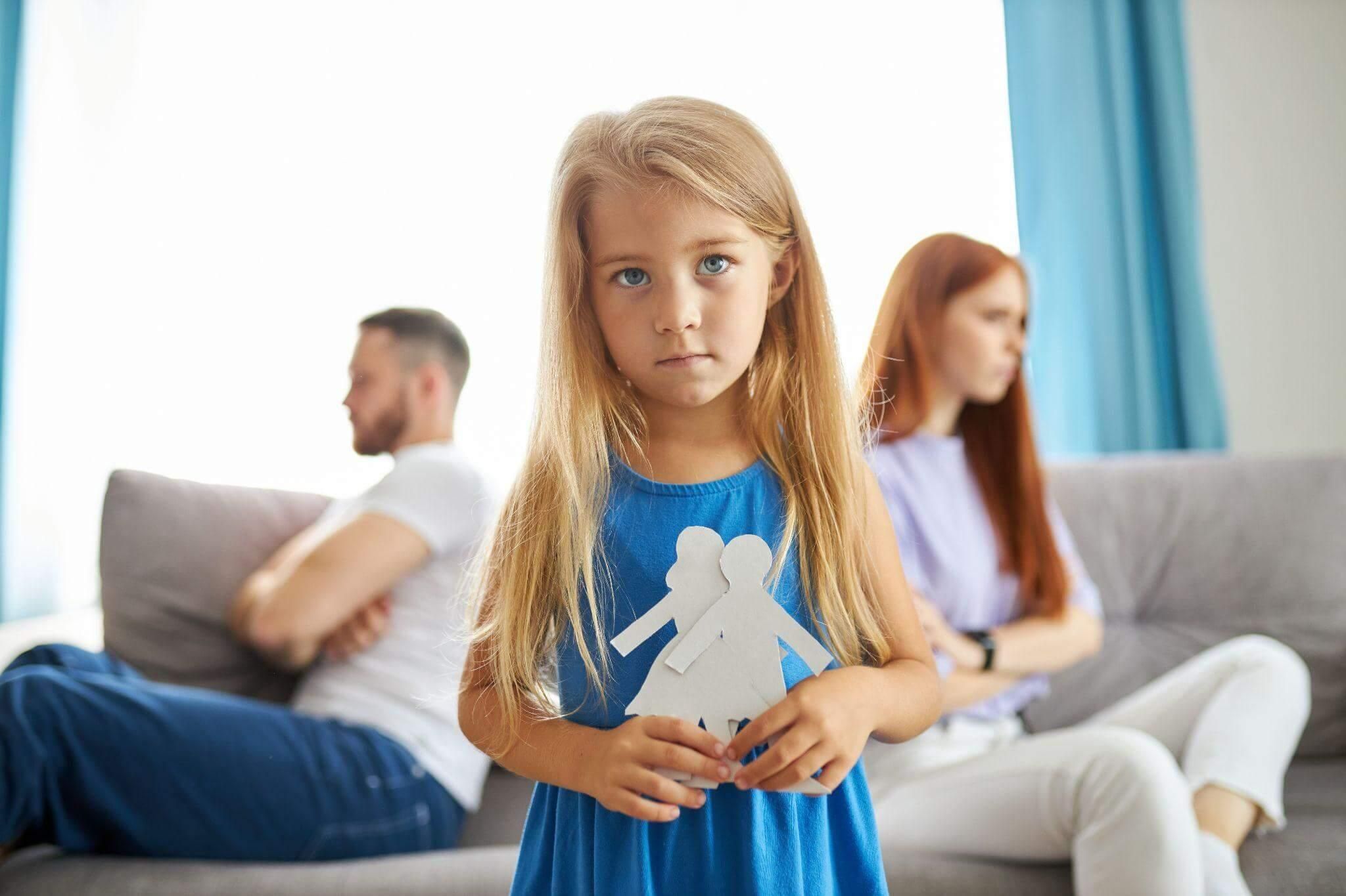 a little girl standing in front of a couch with a paper cutout of a